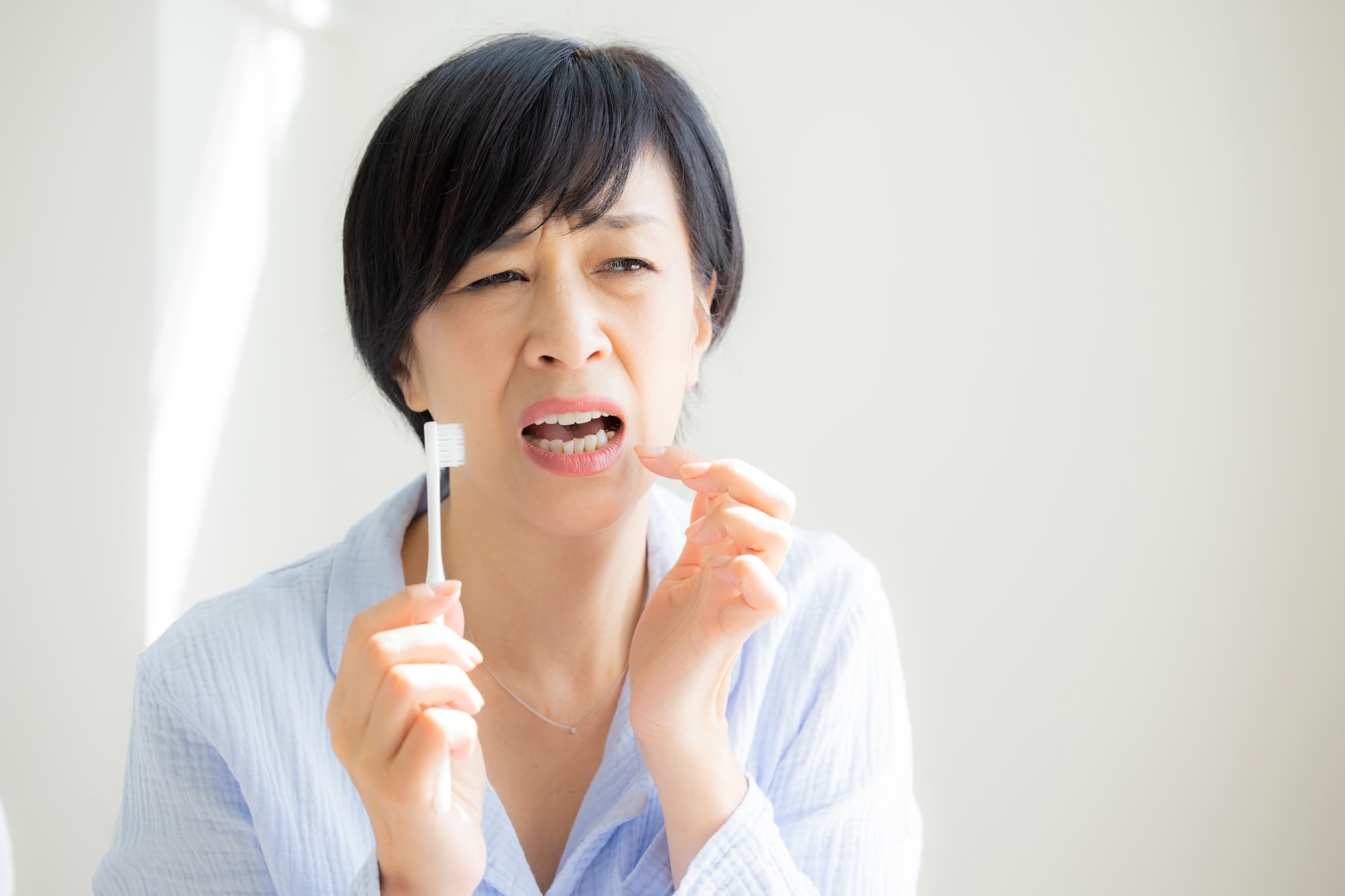 歯磨き時インプラントに違和感を感じ鏡を見る女性