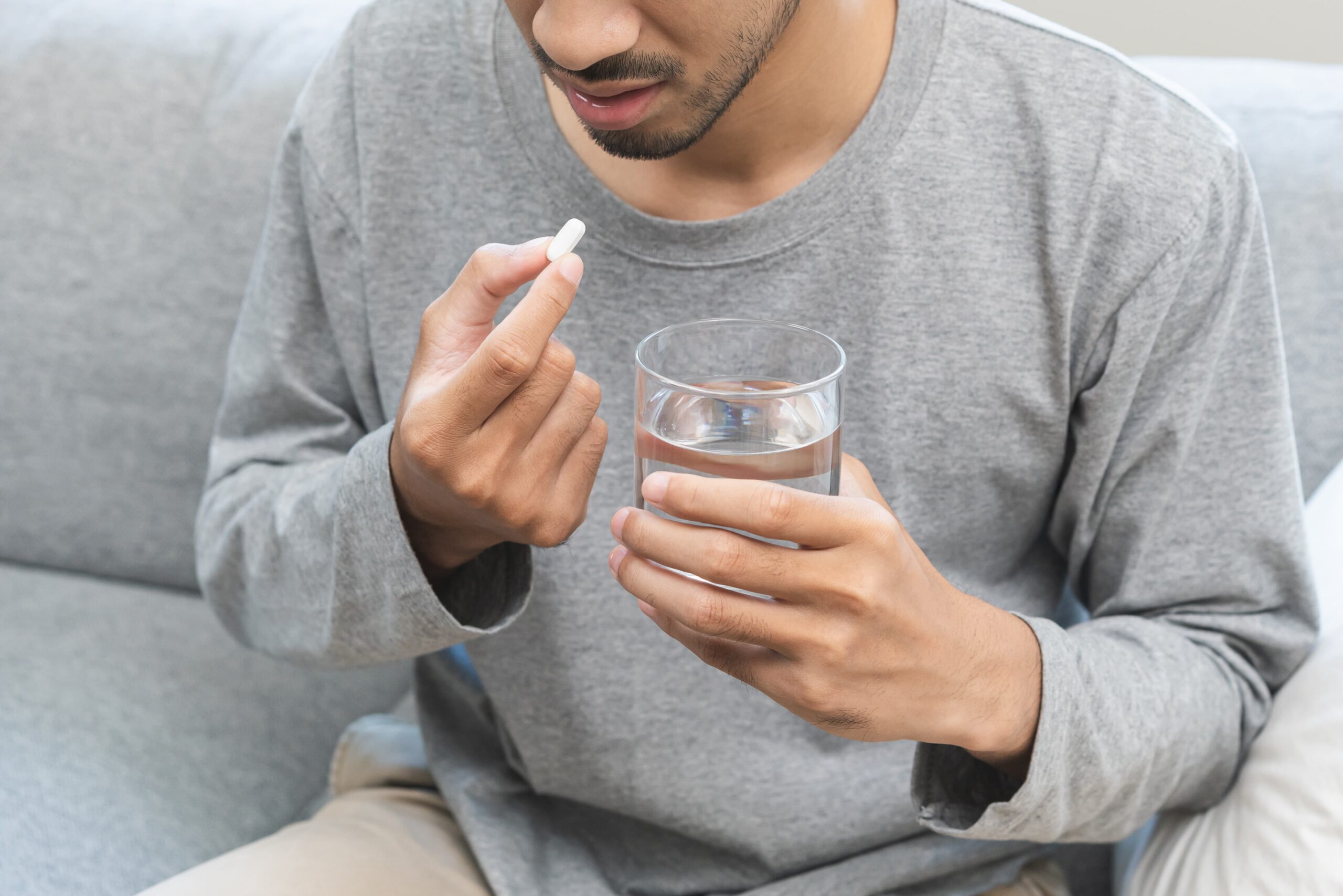 痛み止めを飲んでいる男性