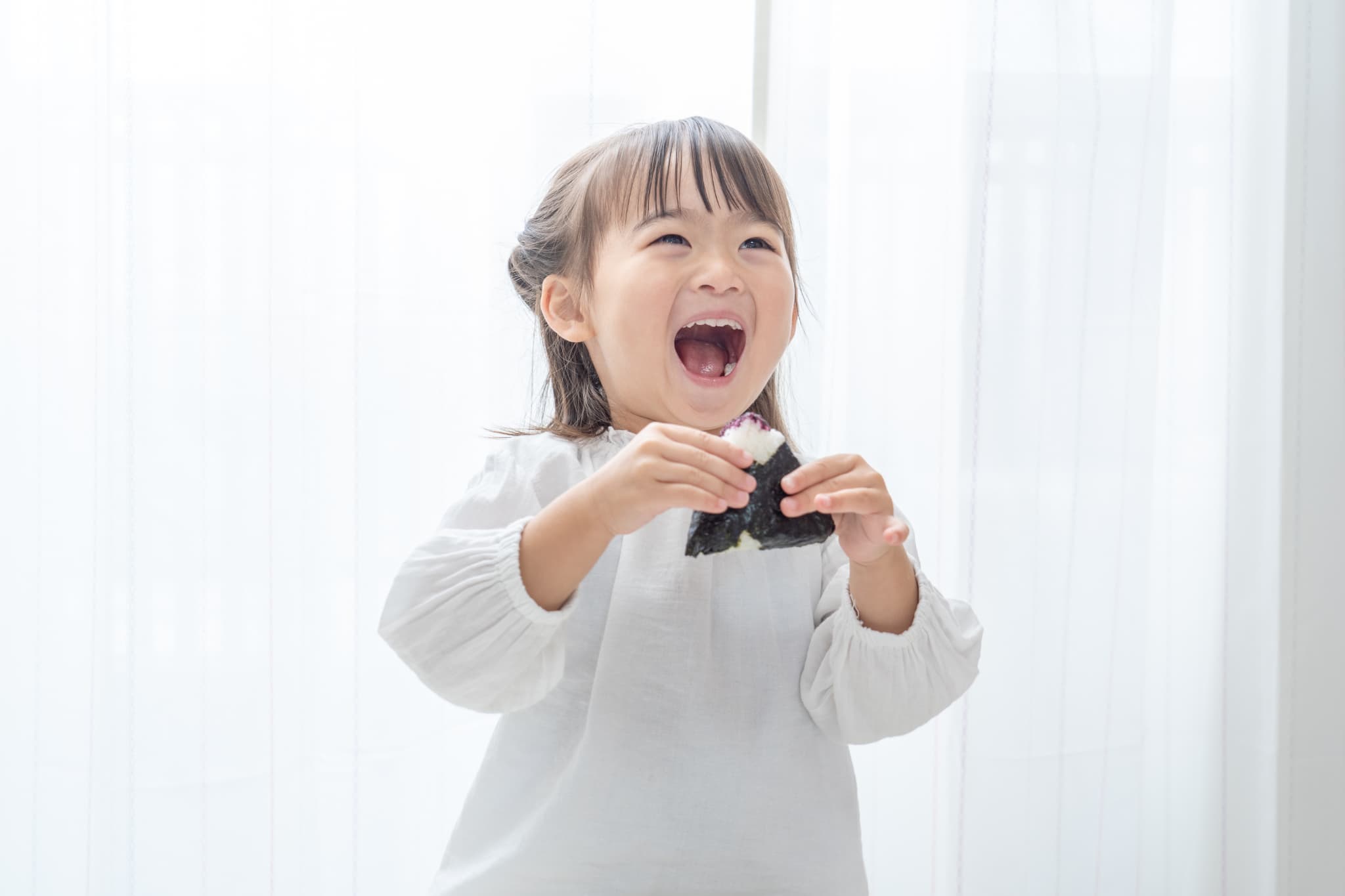 MFTでしっかり噛めるようになり大きなお口でおにぎりを食べる子ども