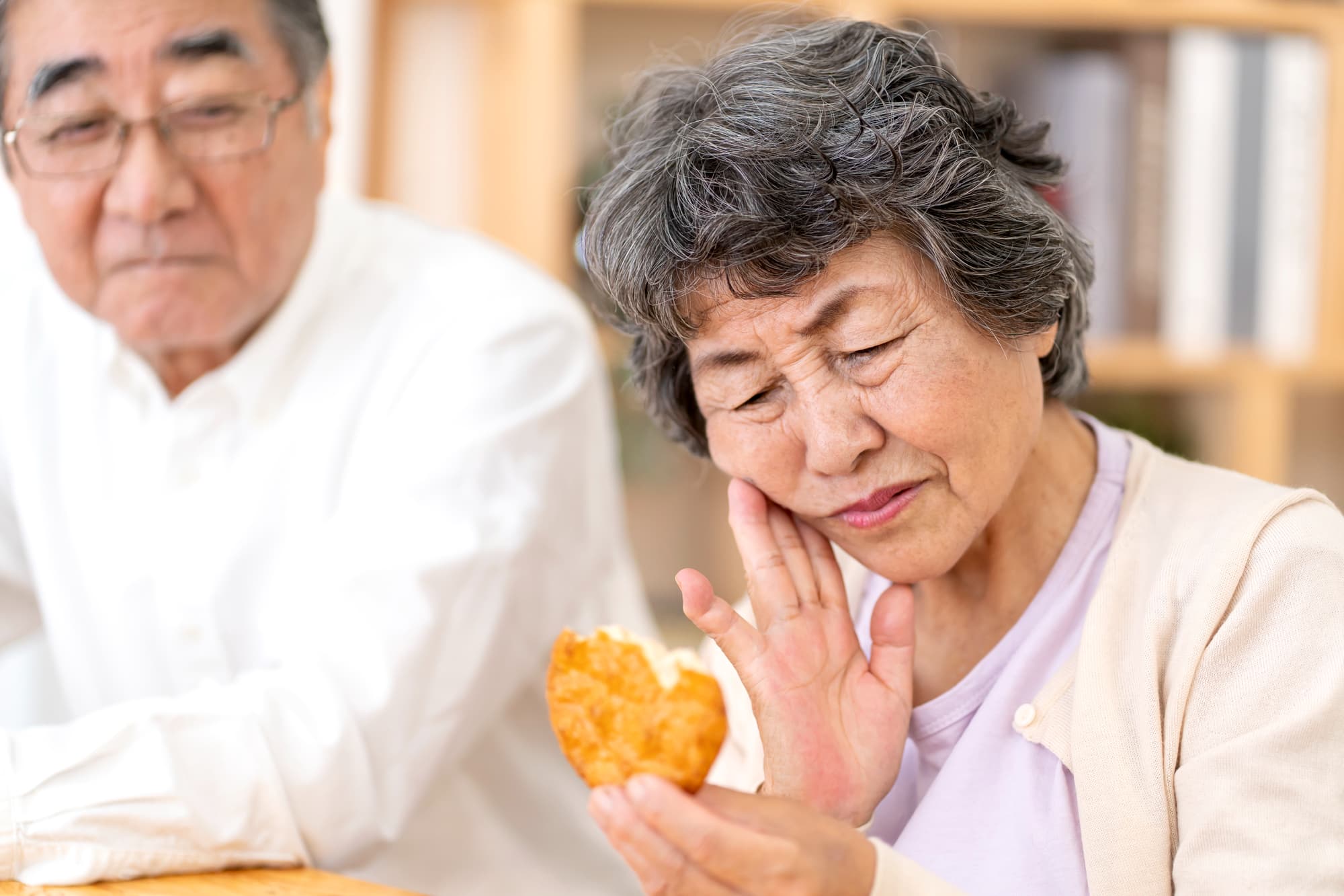 根管治療後に堅いせんべいを食べて違和感を感じる女性